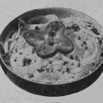 An original published image of the salad in black-and-white, showing a serving suggestion with the shredded cabbage slaw served in a chilled salad bowl with a pepper ring garnish.
