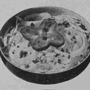 An original published image of the salad in black-and-white, showing a serving suggestion with the shredded cabbage slaw served in a chilled salad bowl with a pepper ring garnish.