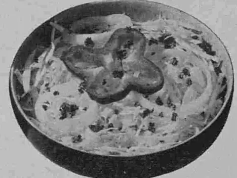 An original published image of the salad in black-and-white, showing a serving suggestion with the shredded cabbage slaw served in a chilled salad bowl with a pepper ring garnish.
